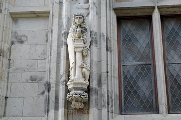 Agrippina-Statue am Rathausturm in Köln: Steinskulptur einer Frau mit Kranz neben verzierten Fenstern.