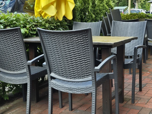 Terasse Restaurant Kibar Ein gemütlicher Außenbereich mit geflochtenen Stühlen unter strahlend gelben Sonnenschirmen.