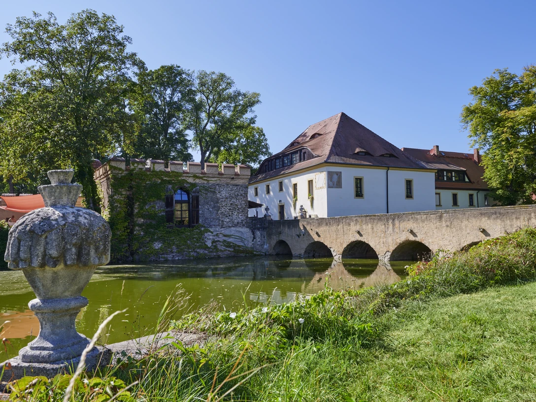 Schlosspark Lampertswalde Die Besucher können sich über das Wasserschloss Lampertswalde mit Wassergraben, Steinbrücke und üppigem Grün an einem klaren, sonnigen Tag freuen.