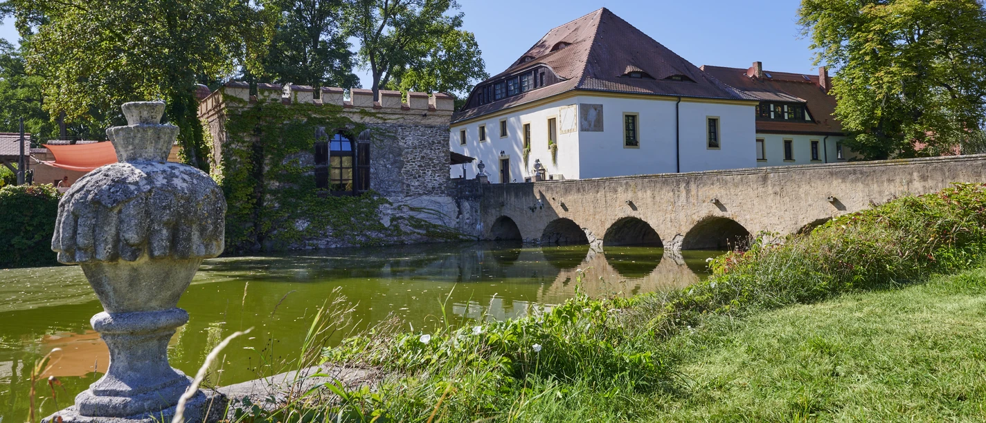 Za jasného slunečného dne se návštěvníci mohou kochat hradním příkopem Lampertswalde s kamenným mostem a bujnou zelení.