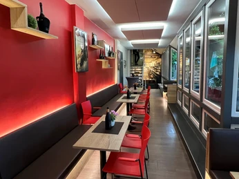 Filmhof Hoya Modernes Café mit roten Wänden, gemütlicher Sitzbereich und stilvoller Holztischdekoration.
