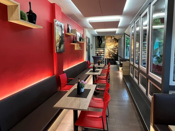 Filmhof Hoya Modernes Café mit roten Wänden, gemütlicher Sitzbereich und stilvoller Holztischdekoration.