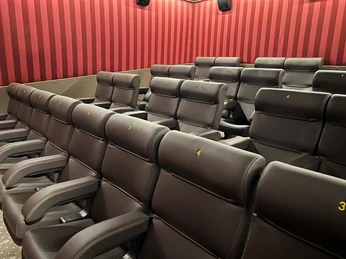 Filmhof Hoya Kino-Innenraum mit modernen, gepolsterten Kinosesseln in Reihen, umgeben von gestreiften Wänden.
