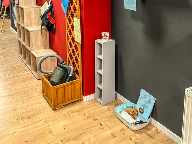 Museum des Schmerzes und der Liebe Ein schmaler Raum mit roten und grauen Wänden, futuristischen Kunstwerken und minimalistischem Dekor.