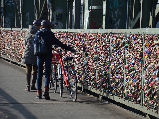 Colonia Aktiv guided bike tours in Cologne People push bicycles along a bridge adorned with countless love locks.