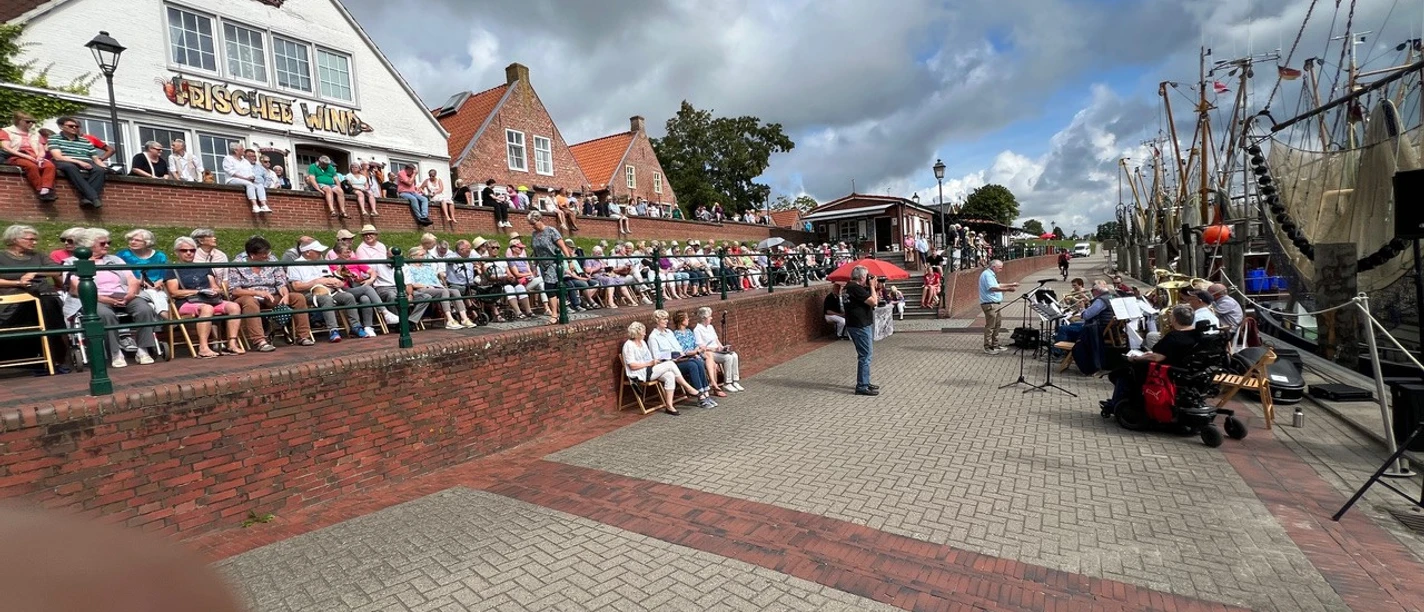 Hafengottesdienst Greetsiel Besucher beim Hafengottesdienst in Greetsiel. Eine Kapelle spielt am Kai neben den Fischkuttern.