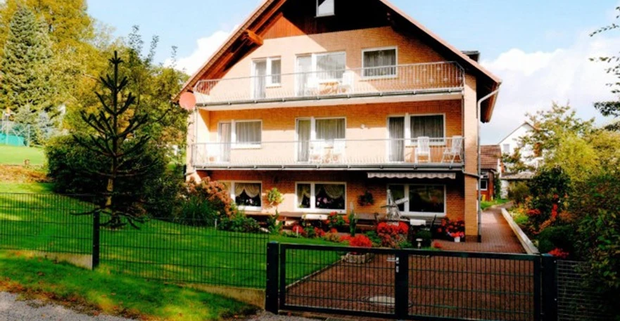 FH Brinks.jpg Drei-stöckiges Ziegelhaus mit Balkon und umgebendem Garten; sonniger Tag mit leichter Bewölkung.