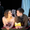 Der Vorleser, Neues Theater Espelkamp "Zwei Schauspielende auf einer Bühne, eine Frau im ärmellosen Kleid, ein Mann liest aus einem Buch."