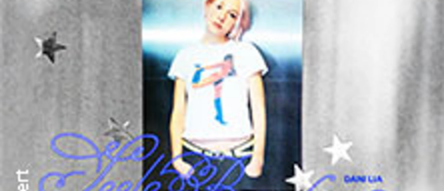 Musikerin vor silbrigem Hintergrund und weißen Sternmotiven, trägt weißes Shirt mit bunter Grafik.