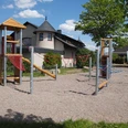 Spielplatz Alsweder Ring in Lübbecke Spielplatz mit modernen Klettergerüsten aus Holz und Seilnetz, umgeben von Wohnhäusern und Bäumen.