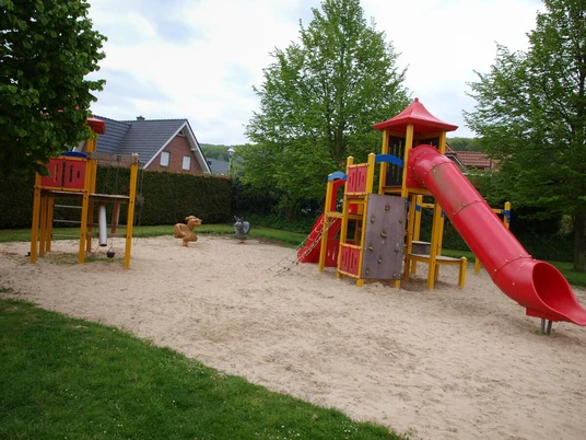 Spielplatz Am Wittelsbach in Lübbecke Spielplatz in Lübbecke mit Klettergerüst, Rutsche und Schaukeltieren auf Sandboden.