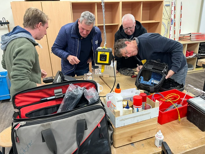 repair-cafe-bad-zwischenahn-elektrogeraete.jpg Vier Männer arbeiten konzentriert in einem Repair Café. Auf dem Tisch liegen Werkzeuge und Elektronik.