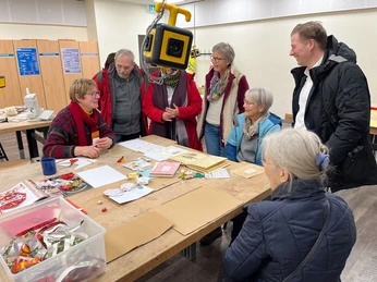 repair-cafe-bad-zwischenahn-basteln.jpg Menschen basteln lächelnd im Repair Café, umgeben von Materialien. Ein Gefühl von Gemeinschaft und Kreativität füllt den Raum.