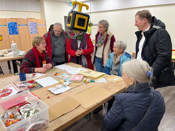 repair-cafe-bad-zwischenahn-basteln.jpg Smiling people tinkering in the Repair Café, surrounded by materials. A sense of community and creativity fills the room.