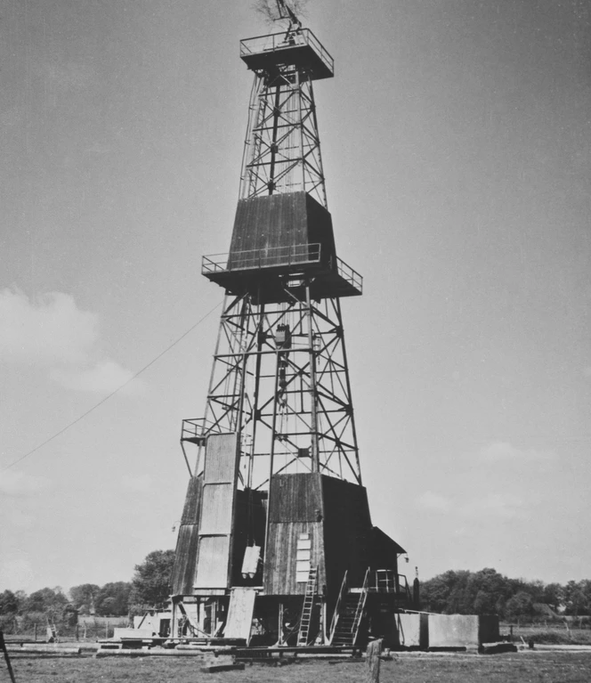 Ab den 50er-Jahren wird im Emsland auch Öl gefördert. Schwarzweißfoto eines hohen Förderturms zur Erdölgewinnung im Emsland der 1950er-Jahre.