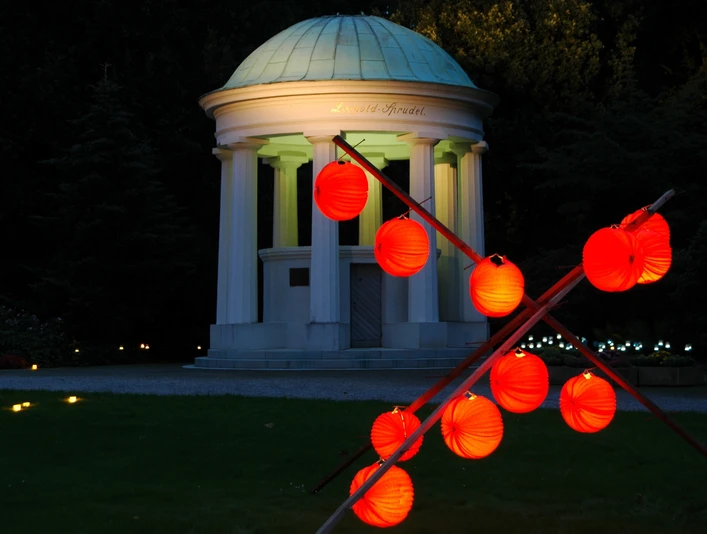 Nacht der 10000 Kerzen ©Staatsbad Salzuflen GmbH Beleuchteter Kurpark mit rotem Laternenvorhang und beleuchtetem Pavillon vor nächtlichem Himmel.