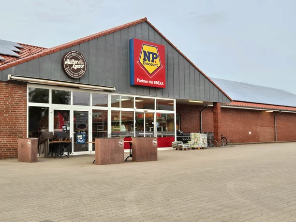 Backsteinfabrikgebäude mit Edeka-Partner NP Discount, Bäckerei, frei begehbar, Personen draußen.
