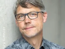 Porträt eines grauhaarigen Mannes mit Brille vor hellem Hintergrund