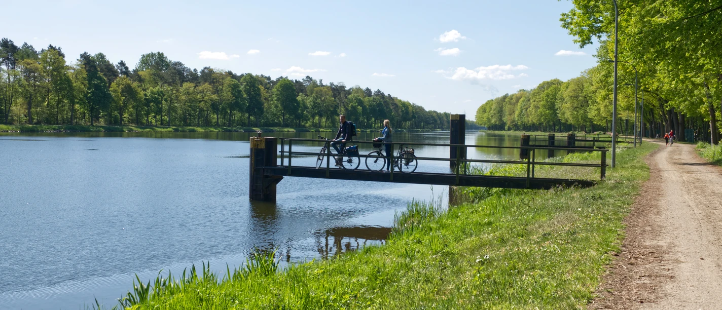 Radfahren im Emsland – Unterwegs am Dortmund-Ems-Kanal ©Emsland Tourismus GmbH (4).jpg Zwei Radfahrende pausieren auf einer kleinen Brücke am Dortmund-Ems-Kanal unter blauem Himmel.