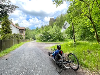 Mit dem Handbike vor den ersten Häusern des Weilers Ottomühle, rechts der Felsgipfel "Großvaterstuhl"