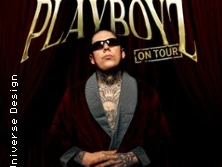 Rufuz, tätowierter Mann mit Sonnenbrille, vor einem braunen Vorhang.