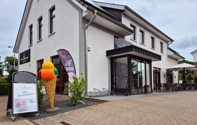Außenansicht Bäckerei-Cafe Schultze Mühlenfeld Einladendes Eiscafé mit modernen Sitzmöglichkeiten und bunter Eisdeko im Vordergrund.