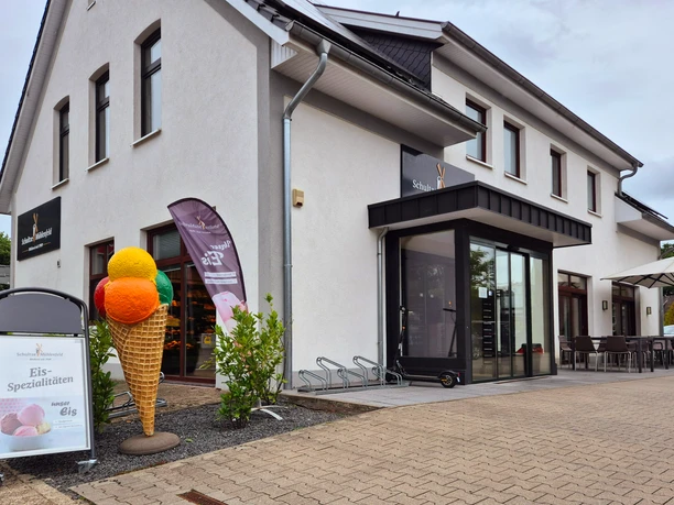 Außenansicht Bäckerei-Cafe Schultze Mühlenfeld Einladendes Eiscafé mit modernen Sitzmöglichkeiten und bunter Eisdeko im Vordergrund.