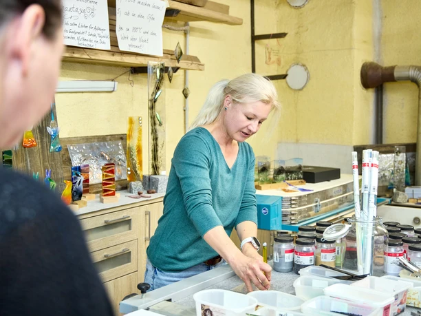 Sonnenberg Glas Eine Frau arbeitet konzentriert in einer Glaswerkstatt.