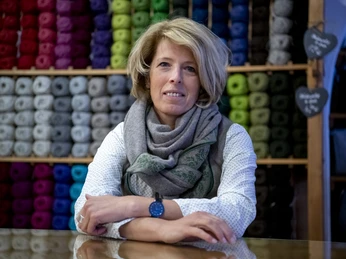 Werdenfelser Schafwoll-Laden Geschäftsinhaberin vor buntem Garnregal im Werdenfelser Schafwoll-Laden.