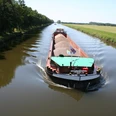 Schleusenkanal Balge Een vrachtschip glijdt over een rustig kanaal, omringd door groene bomen en open velden.