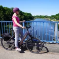 Eine Radfahrerin steht auf einer blauen Brücke und blickt auf den Schleusenkanal Balge.
