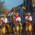 Karneval ©Stadt Delbrück Karnevalsumzug in Delbrück mit verkleideten Reitern auf Pferden in einer belebten Straße.