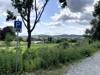 Wohnmobilstellplatz_Stadt-Borgholzhausen (6).JPG Landschaftliche Ausblick mit Wohnmobilstellplatzschild, grünen Feldern und malerischen Hügeln.