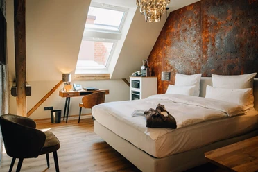 Gästezimmer in der Marienburg Monheim Modern eingerichtetes Gästezimmer mit einem großen Bett, Schreibtisch und warmem Lichteinfall.