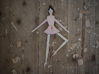 Oberammergauer Schnürlkasperl Holzmarionette in Rosa auf Holztisch, umgeben von Holzspänen.