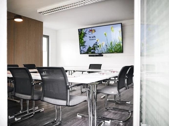 In Via Hotel Moderner Konferenzraum mit ergonomischen Stühlen, großem Bildschirm und natürlichem Licht.