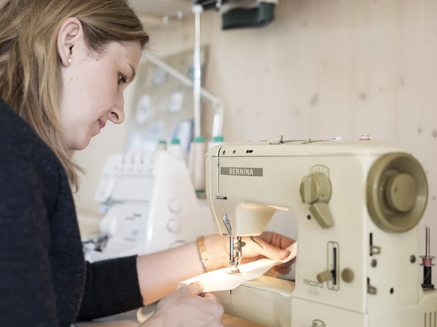 Karlmeise Eine Person näht an einer Bernina-Nähmaschine in einem hellen Raum.
