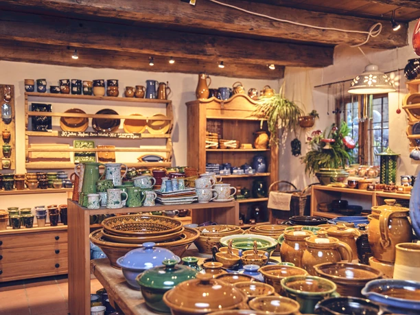 Hafnerei Glentleiten Töpferwaren in einem warm beleuchteten Raum mit Regalen voller Keramik und Pflanzendekoration.