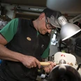 Da Doni Handwerker in Werkstatt drechselt Holz auf einer Maschine unter einer Lampe.