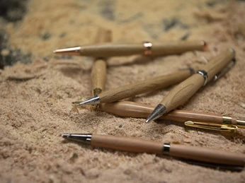 Da Doni Handgefertigte Holzstifte liegen auf Sägemehl in einer Werkstatt.