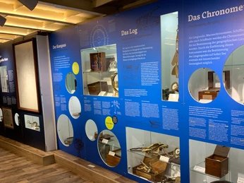 Ausstellungswand im Schifffahrtsmuseum Haren mit historischen Navigationsinstrumenten und Tafeln.