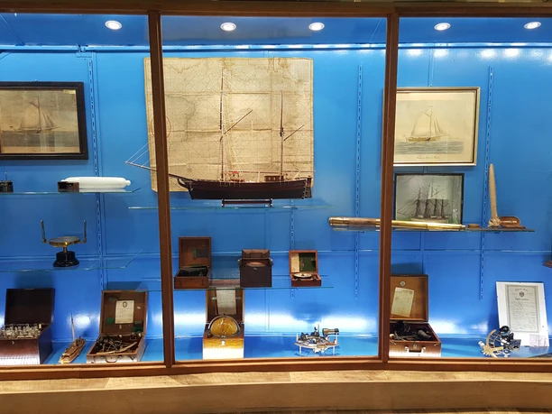 Tentoonstellingswand met scheepsmodellen, oude navigatie-instrumenten en zeekaarten in het museum.
