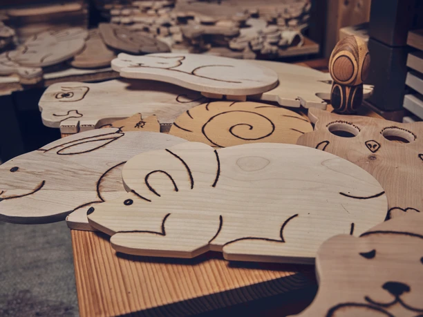 Holzmasken Brauner Holzmasken in Tierformen, detailreich geschnitzt, liegen auf einem Tisch in einer Werkstatt.