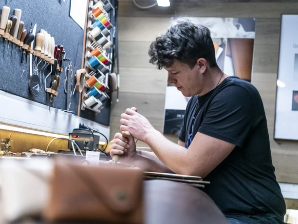 Andalui Design Ein Handwerker arbeitet konzentriert an einem Lederprojekt in einer Werkstatt.