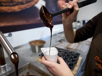 Chocolaterie Amelie Schokolade wird in einem Löffel gehalten und in einen Becher gegossen.