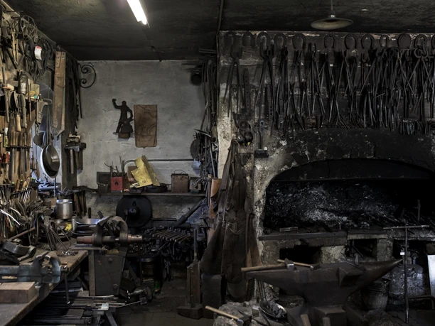 Aberl Metallgestaltung Ein traditioneller Schmiederaum mit Werkzeugen und einem Schmiedeofen.