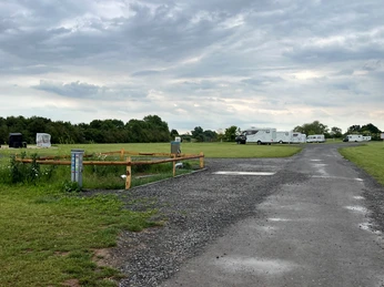 WoMo Weser-Ufer-Urlaub Stellplatz für Wohnmobile am Weser-Ufer mit Stromsäulen, umgeben von grünen Wiesen und Büschen.