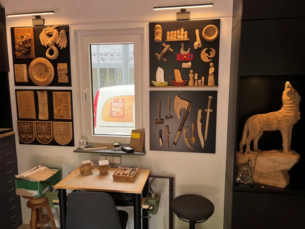 Vielfältige Holzkunstwerke und Werkzeuge dekorieren eine Wand in einem handwerklichen Studio.