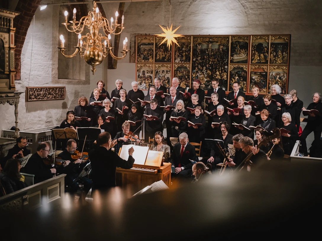 Kantorei St.-Johannes 2024-12 Weihnachtsoratorium.jpg Chor und Orchester führen ein Weihnachtsoratorium in der festlich beleuchteten Kirche auf.