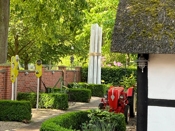 Spargelmuseum Nienburg En rød traktor er parkeret foran indgangen til et museum med en høj aspargesskulptur i haven.